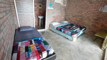 Una habitació amb dos llits, una taula petita i una paret de maó.