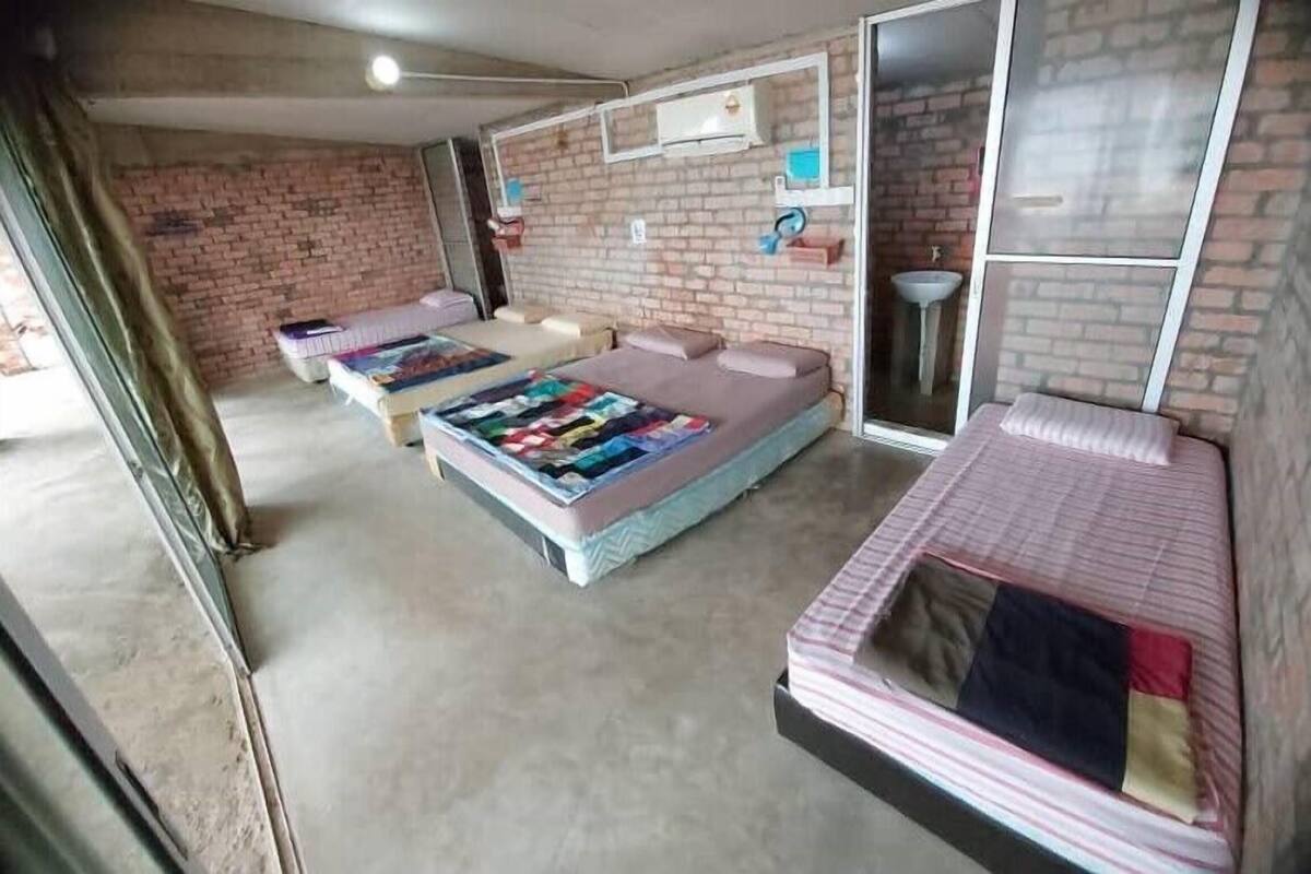 A room with two beds, a brick wall, a window, and a sink.