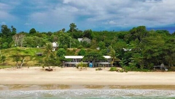 A beachfront property with a sandy beach, a structure with a white roof, and lush greenery. - Hotel O Naga Puri Beach Retreat (Kuala Penyu)