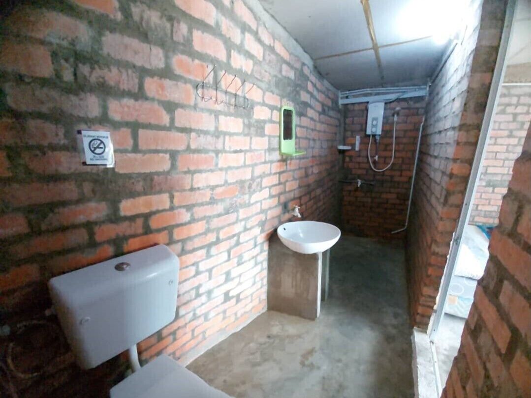 Een compacte, afgesloten badkamer met toilet, wastafel en douche.
