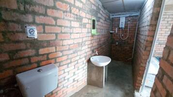 A small, enclosed bathroom with a toilet, sink, and shower area.