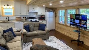 A cozy living room with a sofa, a coffee table, and a TV on a stand. - Lake Cabin with Fantastic View--Kayak, Swim or Fish (Perryville)