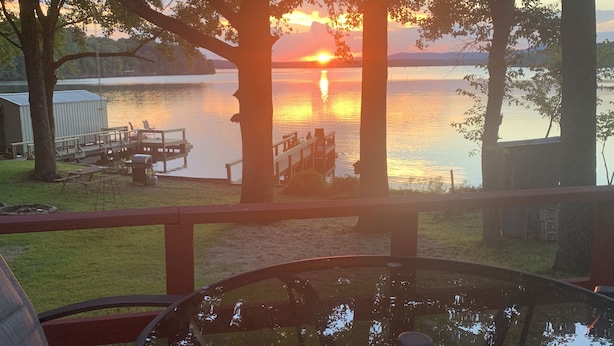 A lakeside view from a deck with a glass table reflecting the sunset. - Lake Cabin with Fantastic View--Kayak, Swim or Fish (Perryville)