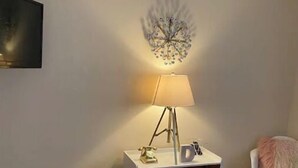 Ein modernes Schlafzimmer mit Bett, Nachttisch mit Lampe, Wanddeko und einem Sessel.