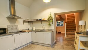 A modern kitchen with white cabinets, a stainless steel range hood, and a countertop with a toaster and kettle. - The Barn (Shrewsbury)