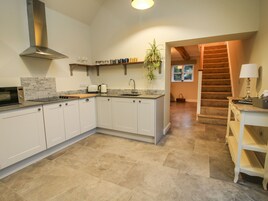 Una cocina moderna con armarios blancos, una campana extractora de acero inoxidable y una encimera con tostadora y hervidor.