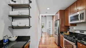 A modern kitchen with stainless steel appliances, wooden cabinets, and a black countertop. - DC’s Southwest and Navy Yard Welcomes You! (Washington)