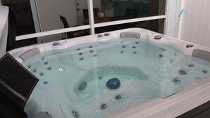 Een bubbelbad met meerdere jets, een glazen deur en uitzicht op de omgeving.