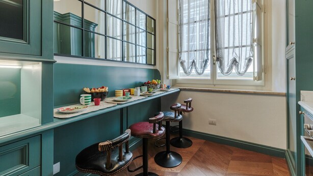 A kitchen with a window, a counter with various items, and two stools.