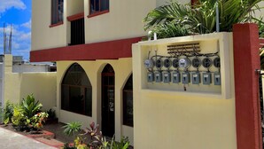 A hotel named "HOTEL NICTE-HA" with a signboard, multiple windows, and an electrical panel on the facade. - Hotel NICTE HA (Xpujil)