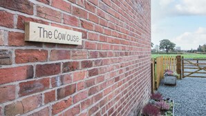A brick building with a wooden sign that reads "The Cowhouse." - Cow'ouse (Shrewsbury)
