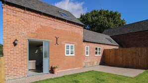 A brick house with a patio, a wooden fence, and a lawn. - Cow'ouse (Shrewsbury)