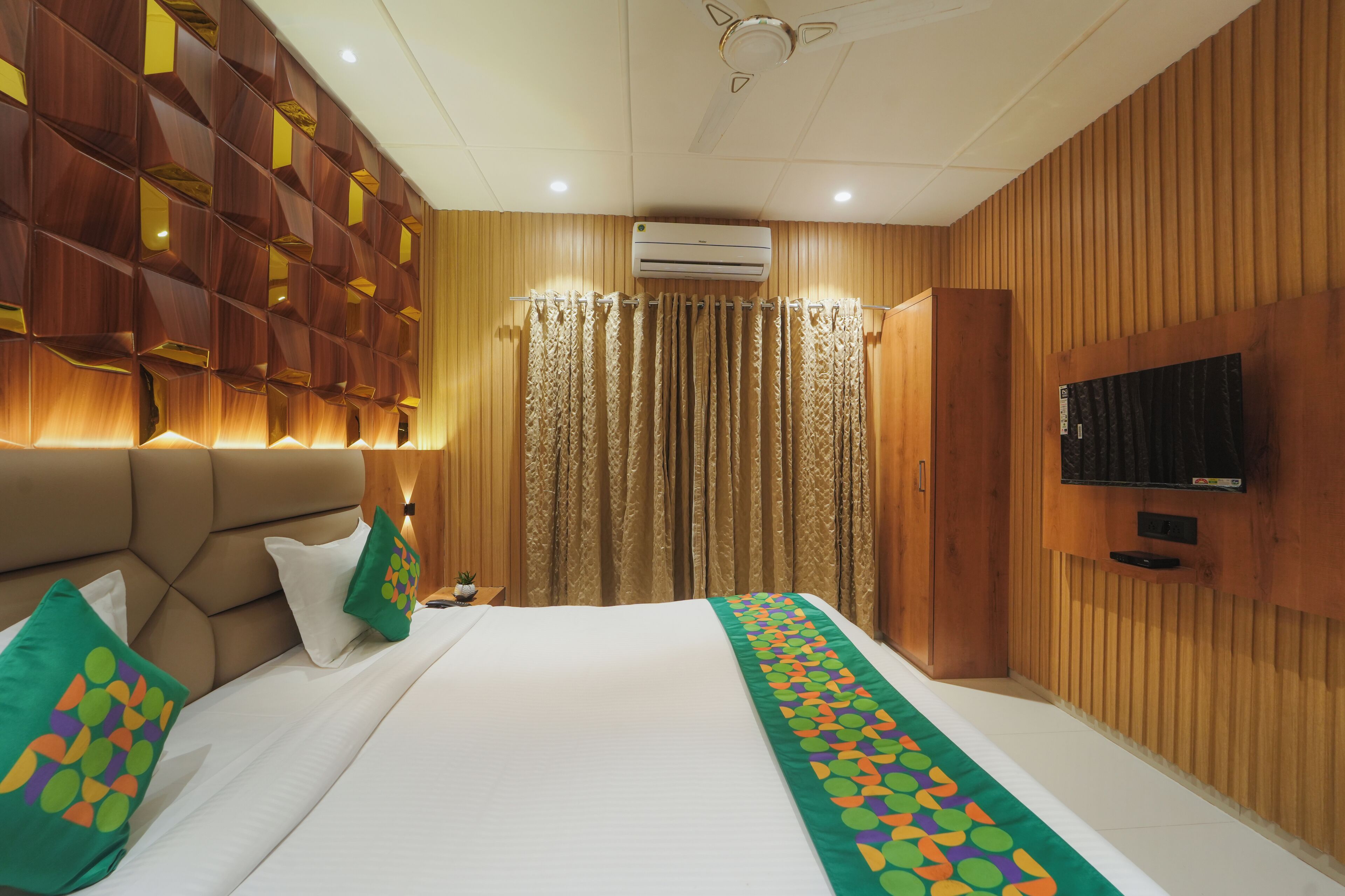 A hotel room with a large bed, wooden paneling, a television, and a curtain.
