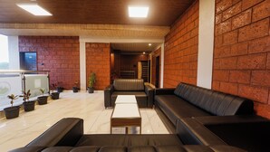 A modern lounge area with leather sofas, a coffee table, and potted plants. - Treebo Iceberg 700Meters From Venna Lake (Mahabaleshwar)