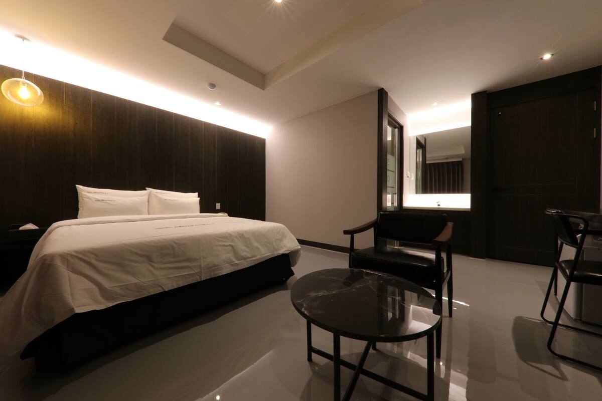 Una habitación de hotel moderna con una cama grande, una mesita redonda y dos sillas.