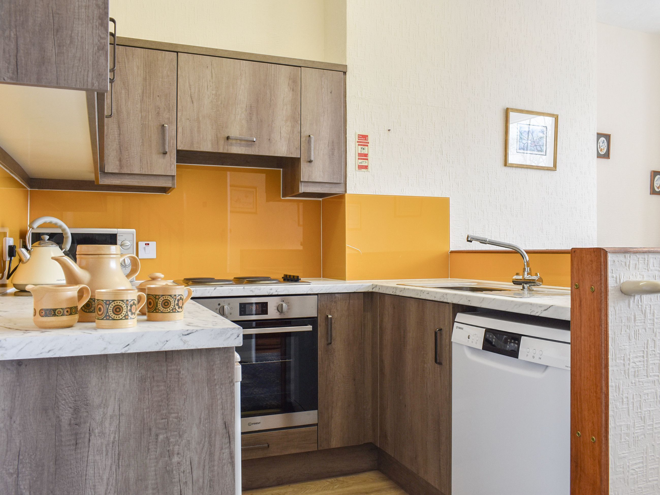 A compact kitchen with wooden cabinets, a microwave, an oven, and a dishwasher.
