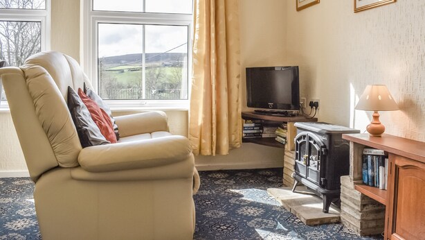 A living room with a sofa, a television, a fireplace, and a window with curtains.