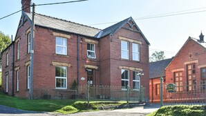 A red brick building with multiple windows and a sign indicating it is 'The Old School.'