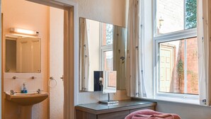 A bathroom with a sink, mirror, and window.