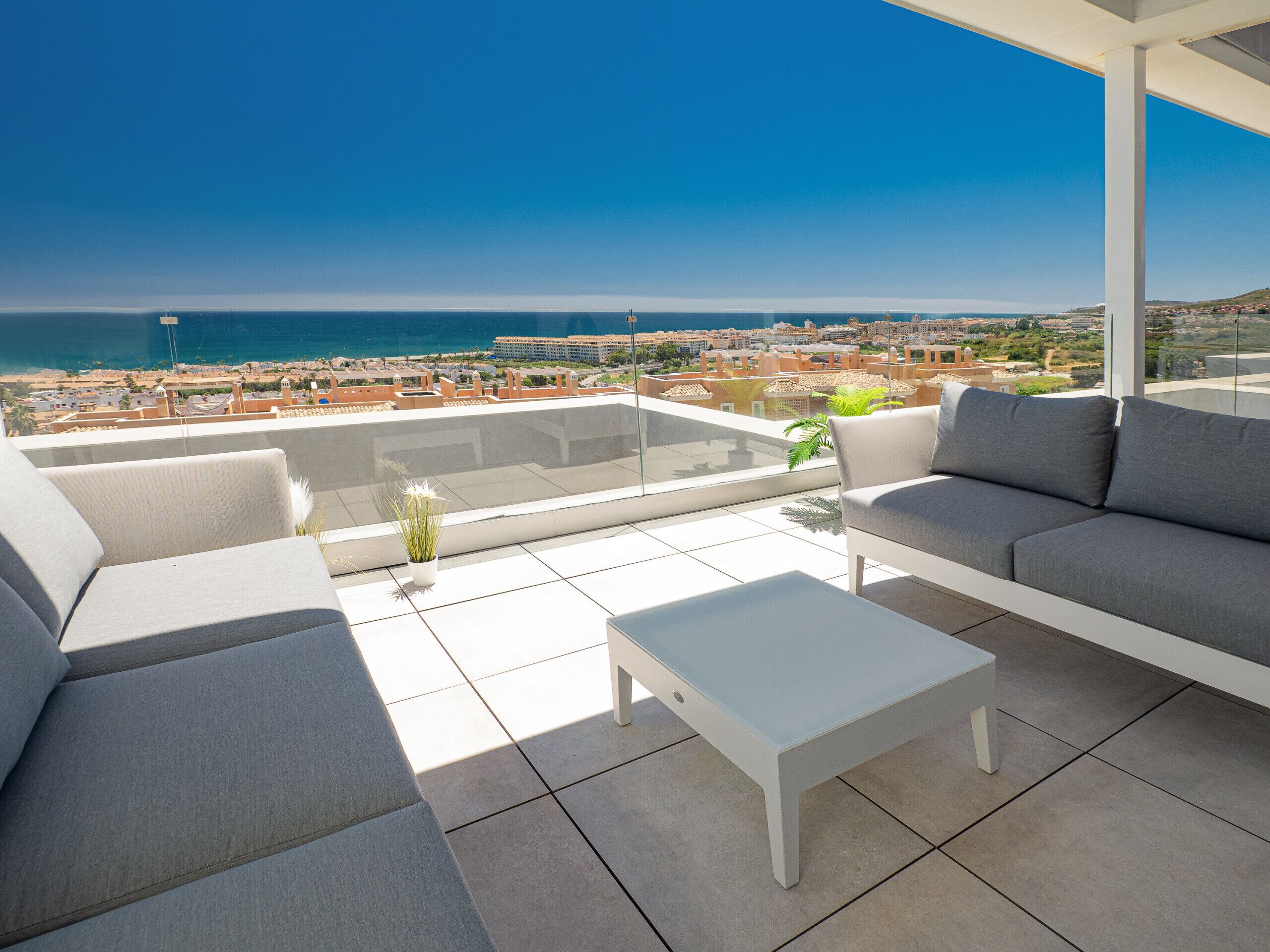 Un área de estar moderna al aire libre con vistas al mar y al paisaje urbano.
