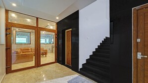 Un interior modern amb un paviment de marbre, una porta de fusta i una escala.