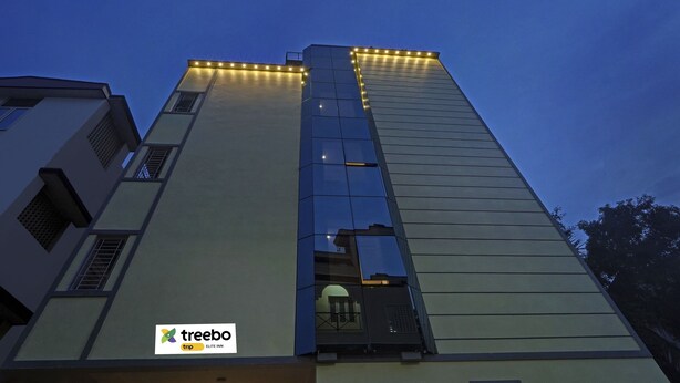 Edifici modern amb façana de vidre i el logotip de 'treebo trip ELITE INN' a la part inferior.