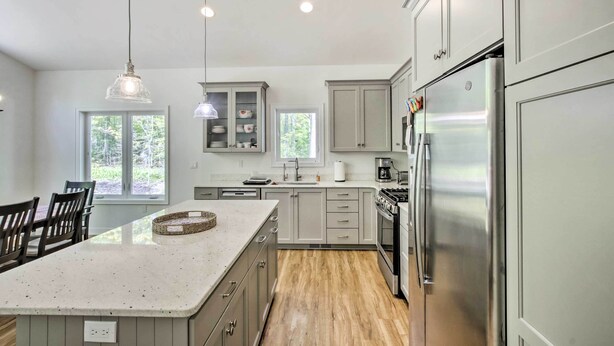 A modern kitchen with a large island, stainless steel appliances, and ample natural light from windows. - Door County Family Home: 3 Mi Whitefish Dunes (Sturgeon Bay)
