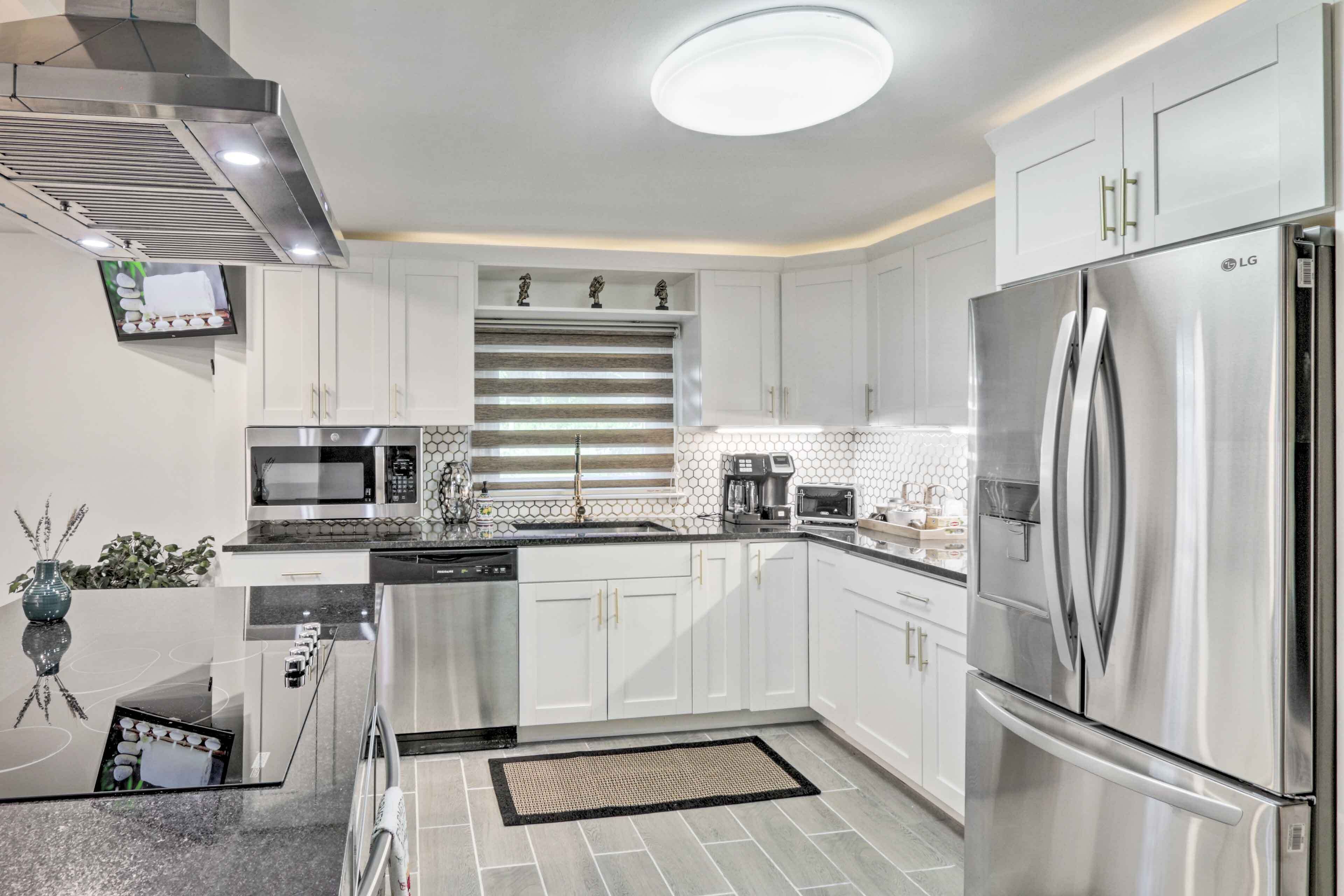 A modern kitchen with white cabinets, stainless steel appliances, and a central island.