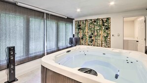 Un baño moderno con una bañera grande, zona de ducha y una pared decorativa con plantas.