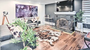 Una sala de estar moderna con chimenea, sofá de cuero y un cuadro abstracto grande.