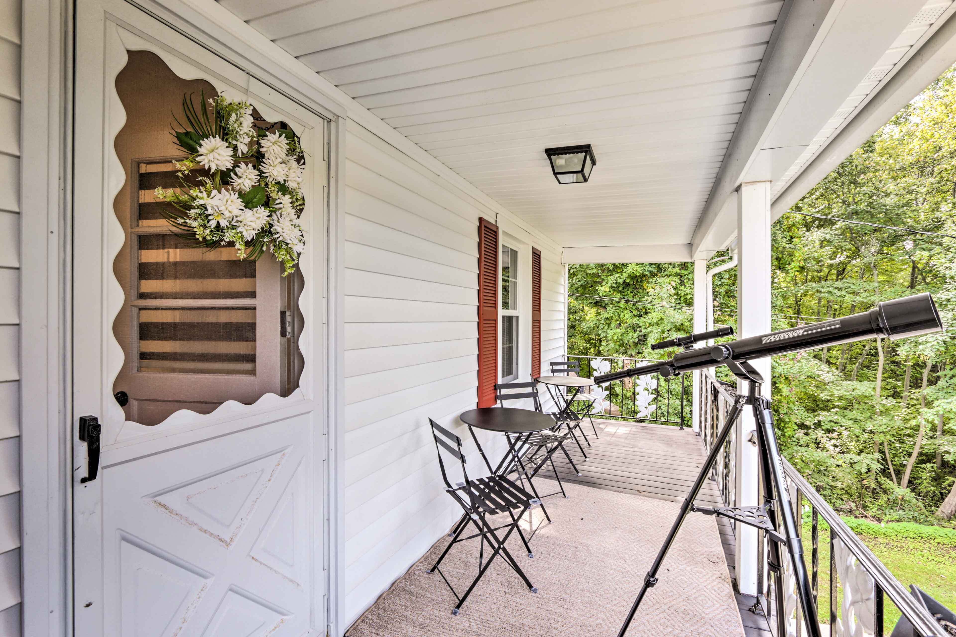 A porch with a telescope, a table, and chairs.