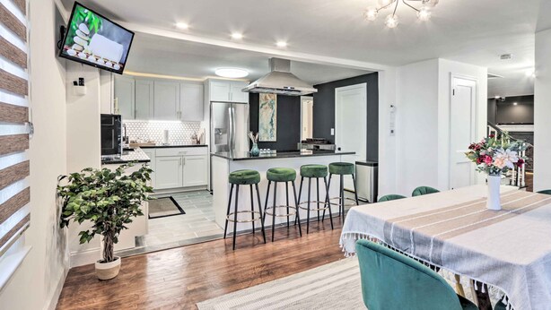 Una cocina moderna con una isla central, taburetes de bar y un comedor con mesa y sillas.
