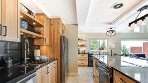 Eine moderne Küche mit Holzschränken, Edelstahlgeräten und einer großen Kücheninsel mit schwarzer Arbeitsplatte.