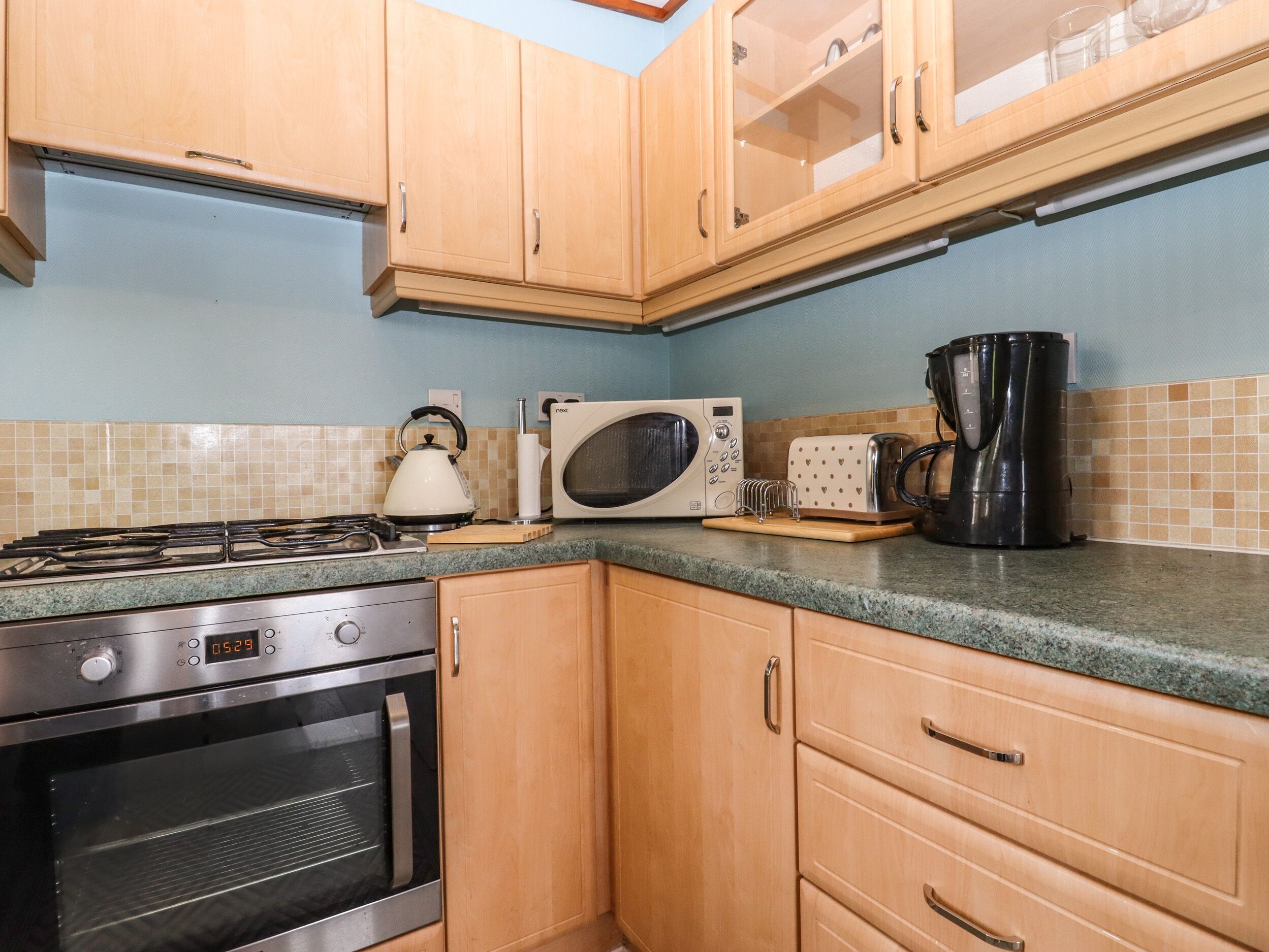 Eine Küche mit Holzschränken, einem Gasherd, einem Backofen, einer Mikrowelle, einem Toaster und einer Kaffeemaschine.