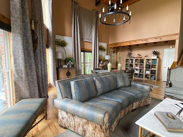 Una sala de estar acogedora con un amplio sofá modular, una mesa de centro de madera y una estantería llena de libros y objetos decorativos.