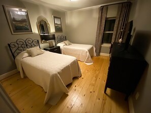 A bedroom with two beds, a desk, a TV, and a window with curtains. - A mountain experience seen from above…a view that takes your breath away! (Jamestown)