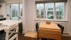 Une cuisine moderne avec une table à manger, des chaises et une vue dégagée sur l’extérieur grâce à une grande fenêtre.