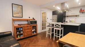 Une cuisine compacte équipée d’un four à micro-ondes, d’un four traditionnel et d’un petit coin repas avec des chaises.
