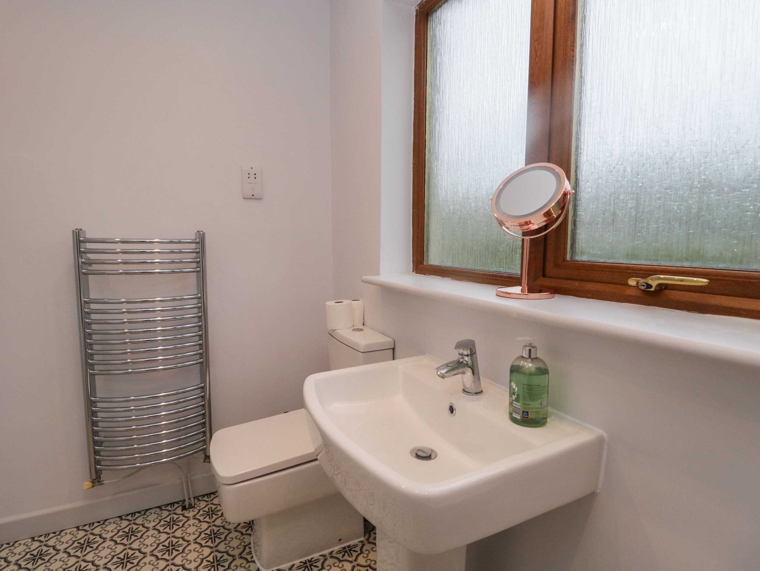 A bathroom with a white sink, a mirror, a toilet, and a towel rack.