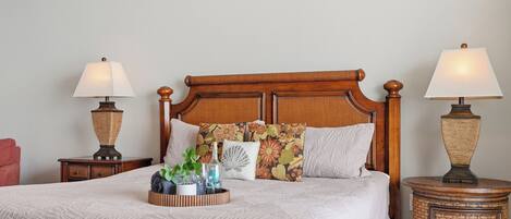 A neatly made bed with a wooden headboard, two bedside tables with lamps, and a bedside plant.