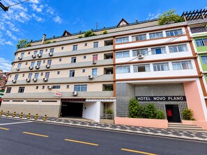 A multi-story hotel with a garage entrance, air conditioning units, and a sign for 'Hotel Novo Plano'. - Hotel Novo Plano (Salvador)