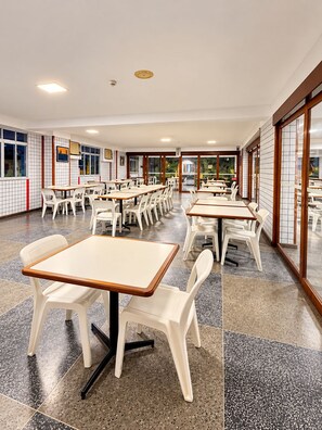 A spacious indoor dining area with multiple tables and chairs, large windows, and a tiled floor. - Hotel Novo Plano (Salvador)