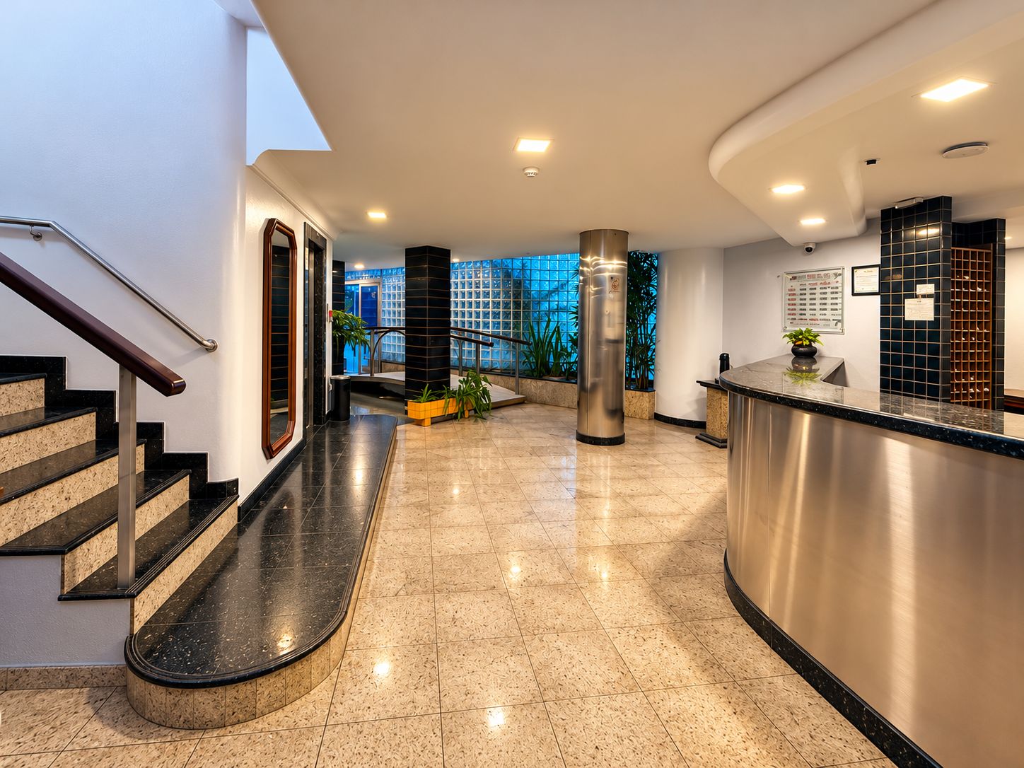 En hotellobby med reception, trappe og udsigt udad.