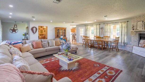 A spacious living room with a large sofa, a coffee table, and a dining area with wooden chairs and a table. - Holiday Decorations l Spacious l 1 Mile to Downtown Bandera l Dog Friendly (Bandera)