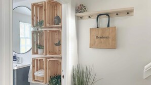 A hallway with a wooden shelving unit holding plants and a 'Denburn' bag. - 2 bedroom accommodation in Colinsburgh, near Elie and Anstruther (Colinsburgh, near Elie and Anstruther)