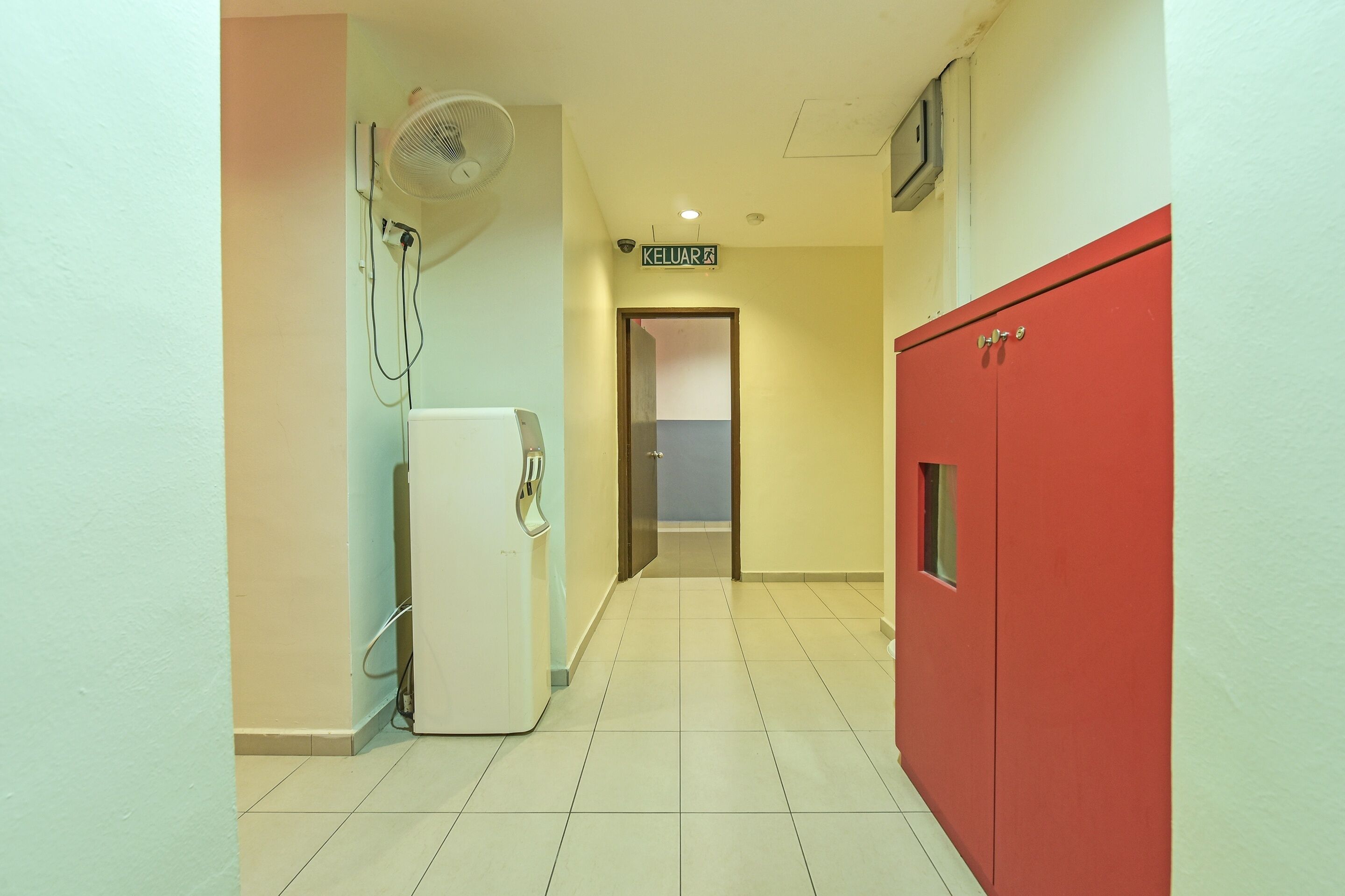 Un pasillo con un refrigerador blanco, un armario rojo y un ventilador de techo.