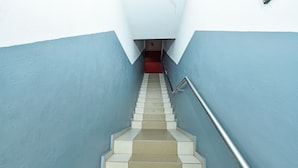 A staircase with alternating beige and white steps, flanked by blue walls, leading to a red carpeted area. - Hotel O M Three Hotel (Sitiawan)
