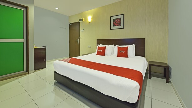 A hotel room with a large bed, a bedside table, a green sliding door, and a framed picture on the wall. - Hotel O M Three Hotel (Sitiawan)