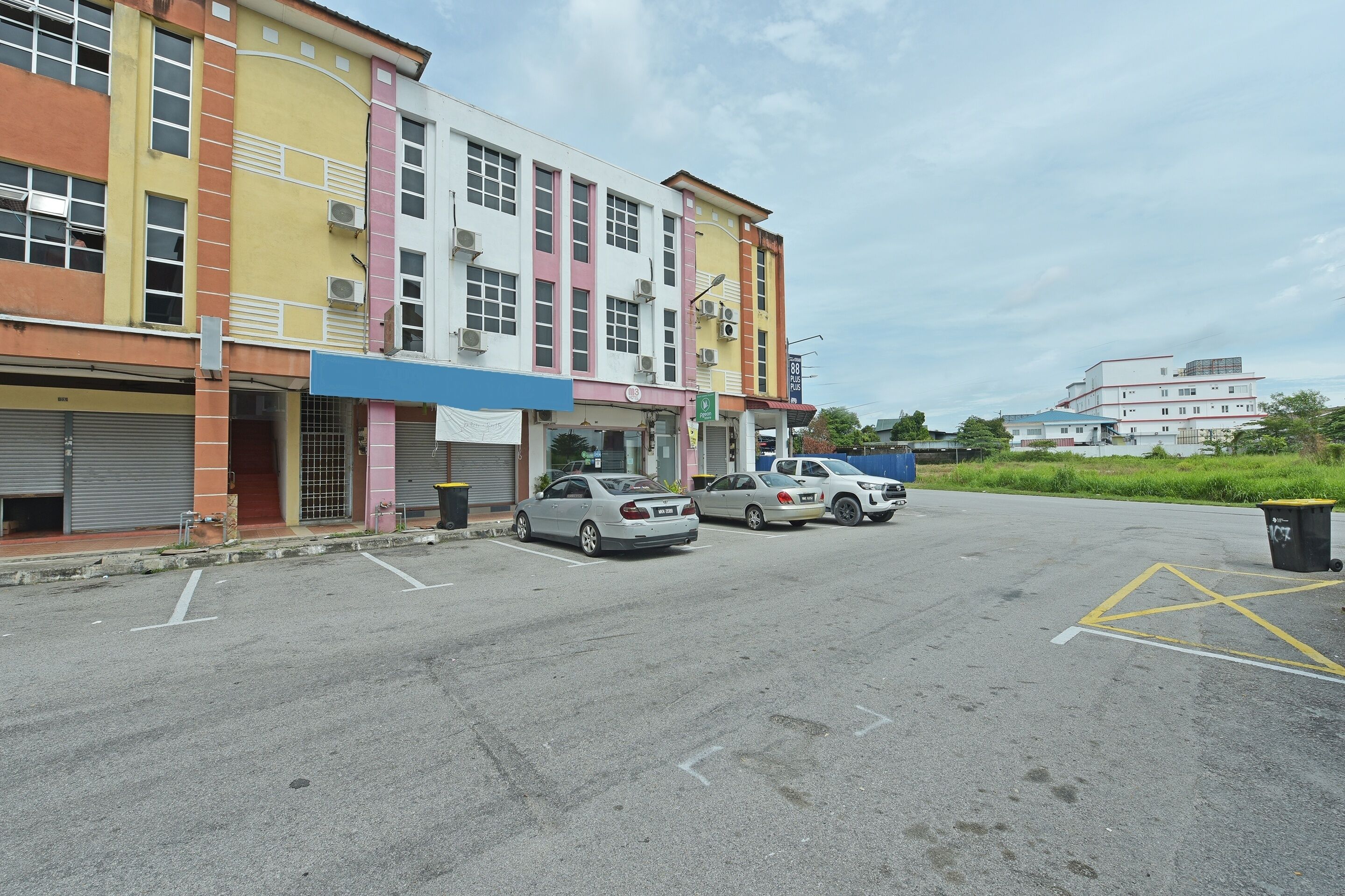 A parking lot with several cars, a building with colorful facades, and a clear sky.