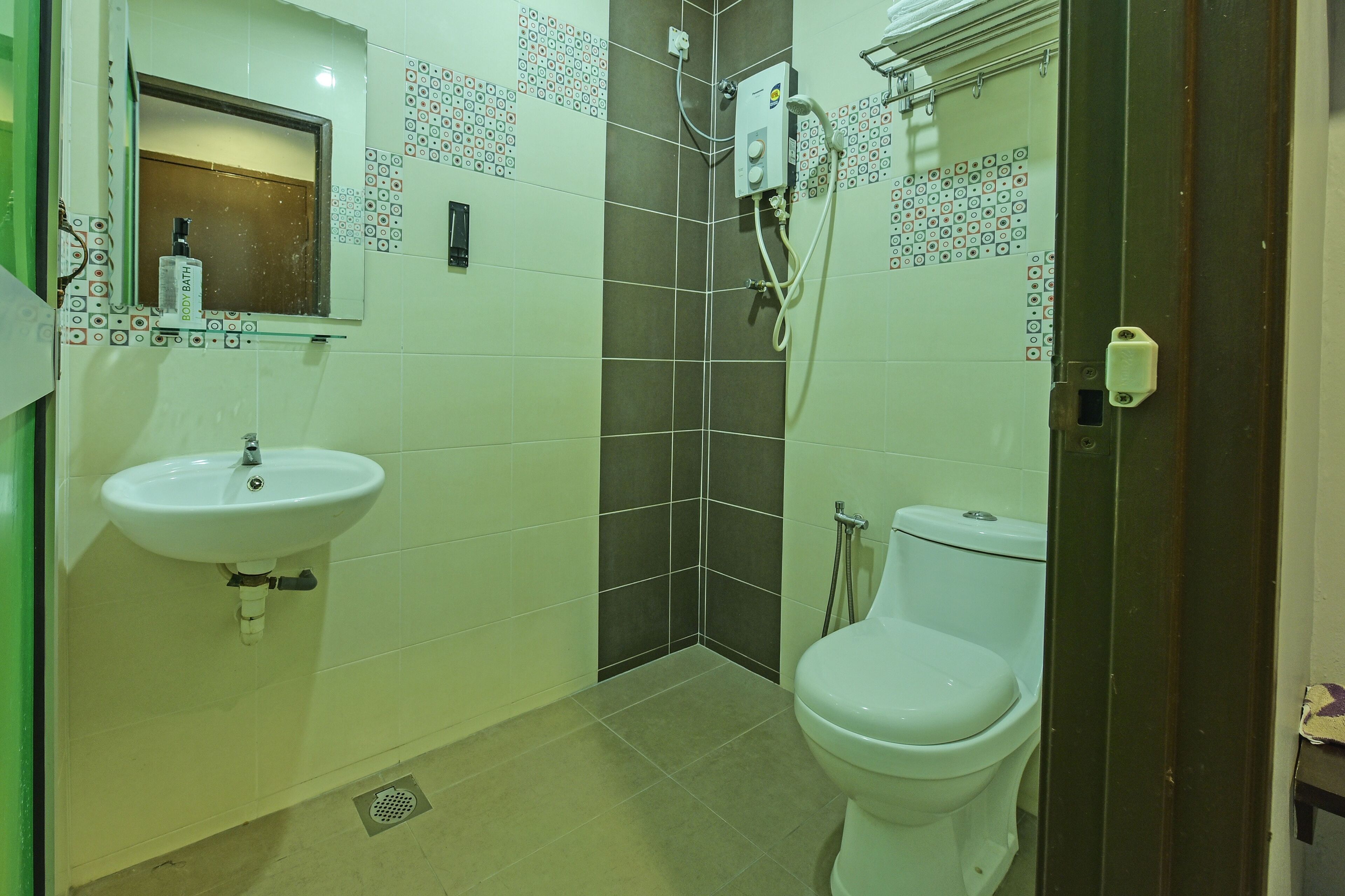 Un baño con lavamanos, inodoro, ducha y espejo.